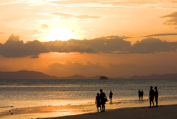 peoples on beach look to sunset
