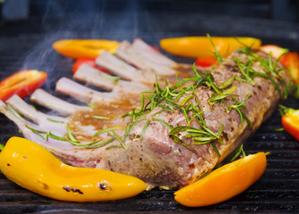 rack of lamb cooking on a grill with bell peppers