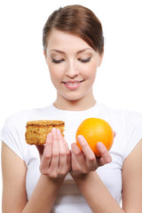 young woman choosing between cake and orange