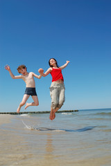 Mother and son jumping on beach