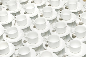 a lot of cups for coffee or tea on a table with spoons and sugar