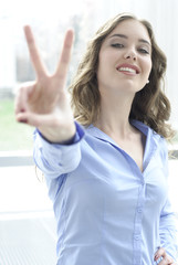 junge frau macht victory zeichen mit fingern und lacht