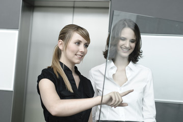junge geschäftsfrauen zeigen auf glas display in büro