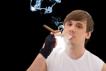 Obraz premium Young man smoking a cigar. Isolated on black