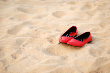 Fototapeta na wymiar Red high-heeled shoes on the beach