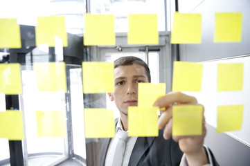 mann in anzug arbeitet hinter scheibe mit post it