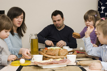 Father and mother with children as they eat breakfast