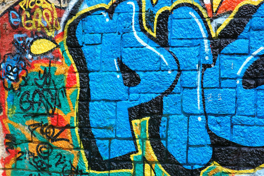 Rough wall surface covered with colorful graffiti.