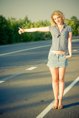 Beautiful country girl hitchhiking on the road