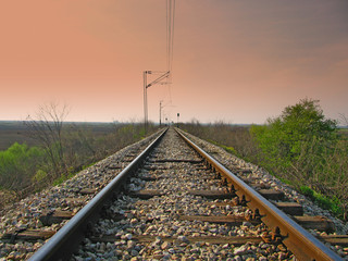 Fototapeta na wymiar Straight train tracks with dark sky above