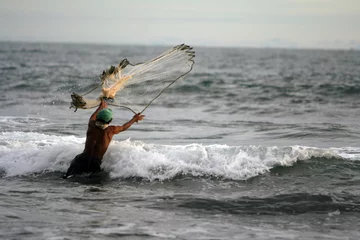 Fotobehang Man fishing in the ocean with a handmade net © SteveB