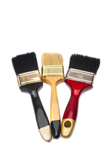 Three paint brushes of different colors on a white background