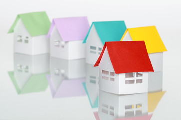 Few toy papery houses with colored roofs standing on white
