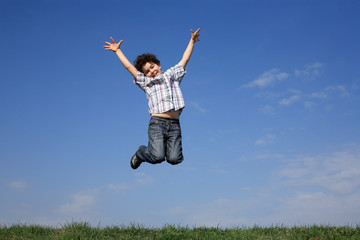 Boy jumping, running against blue sky