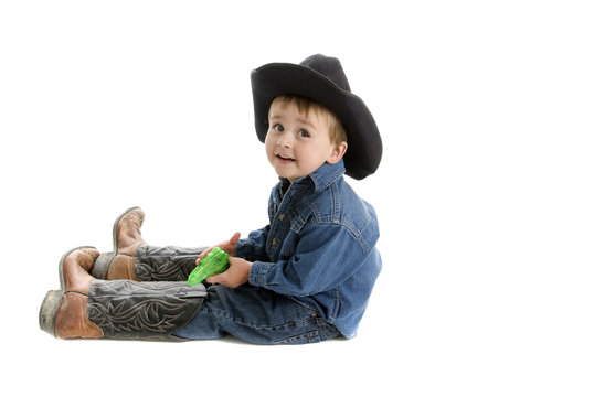 Toddler cowboy with dad's boots and squirt gun