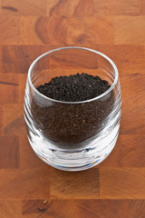 black onion seeds in glass on wooden table