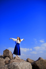 Girl model in a blue dress against a background of blue sky