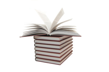pile of books with one book open on white background