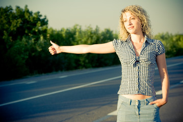 Beautiful country girl hitchhiking on the road