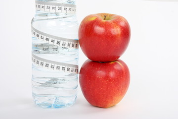 two red apples and bottle of water with measuring tape