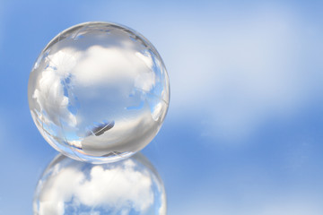 Glassy globe on background with blue sky