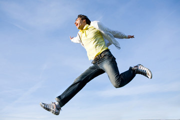 Happy young man - jumping end flies in blue sky