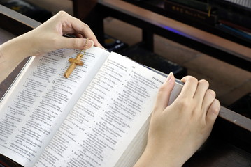 Female hands holding bible on church pew