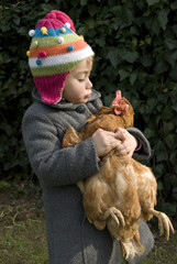Bambina con in braccio una gallina