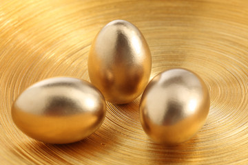 drei goldene Eier auf goldener Schale