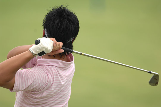 A male golfer hits a ball and is in his backswing.