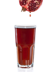Half of pomegranate with drop and glass with juice