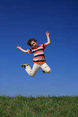 Boy jumping against blue sky