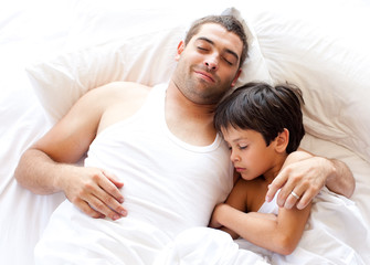 Obraz na płótnie Canvas father and son asleep on bed