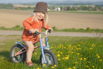 Kind am Laufrad in Blumenwiese