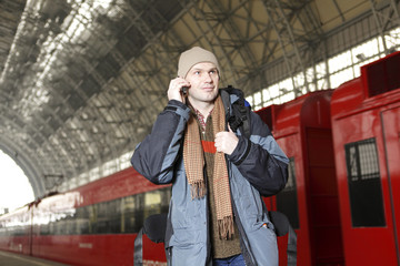 Man with backpack andm mobile phone at the train station