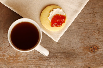 Tea with a butter cookie smothered with cream cheese and jam