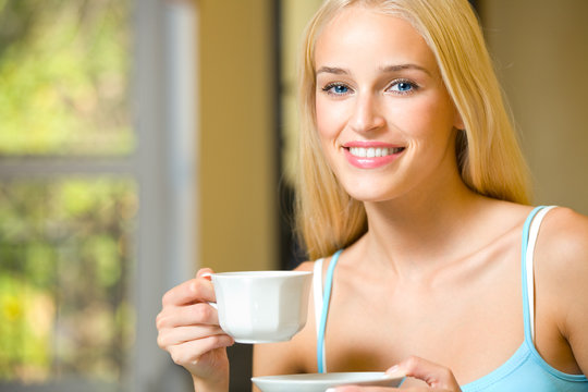 Young beautiful smiling woman with cup of coffee or tea