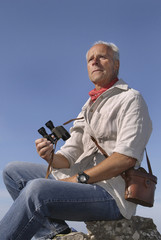 Mature man model posing outdoors with is binoculars