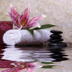 Pink lily flower on white towel and balanced rocks
