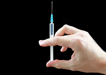 Syringe with medication in hand on black background