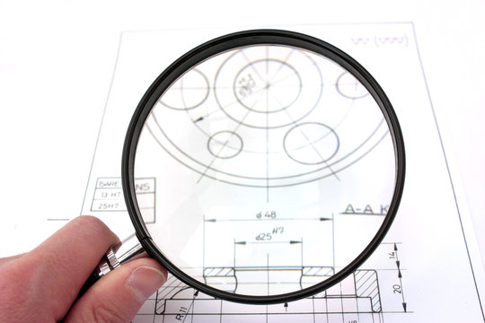 Reviewing technical drawing. Focus on magnifying glass.