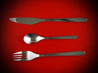 Fork, knife, spoon on red  background