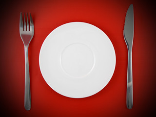 Fork, knife, plate, on red   background