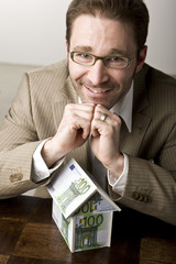 Junger Mann mit Haus aus Geldscheinen