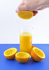 Glass of fresh orange juice with squeeze slice on blue.
