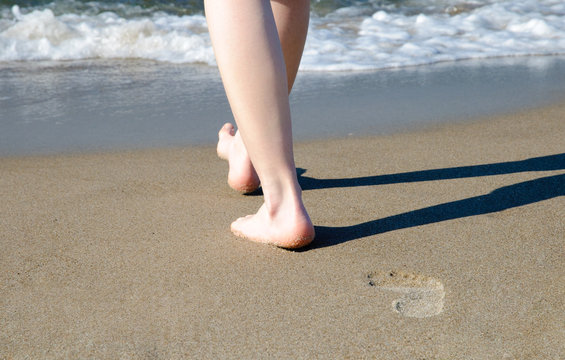 Frau l&auml;uft barfu&szlig; am Strand
