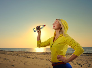 Young woman drinking water after fitness exercise