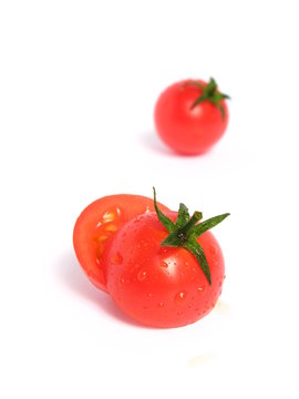 Cherry tomatoes, one cut in half, on white background