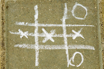 Tic tac toe game drawn with chalk on asphalt