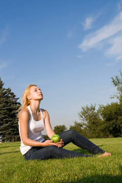 pretty woman eating green apple on the summer glade